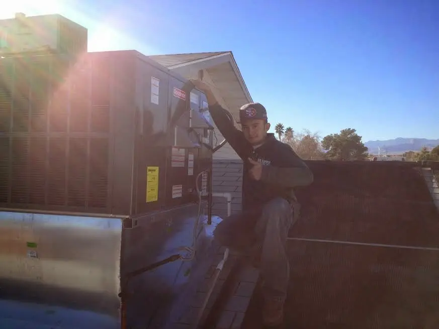HVAC technician performing Air Duct Repair on a rooftop unit in Laurel