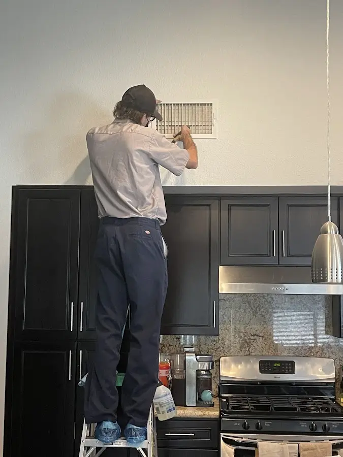Technician inspecting an air vent during HVAC service in Laurel